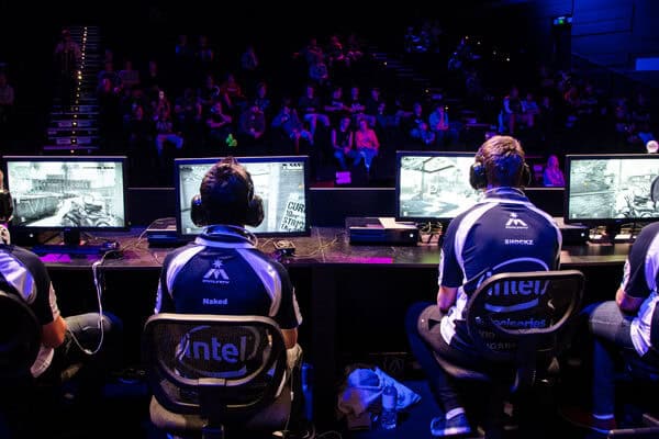 Equipo de gamers en torneo de eSports con monitores y audífonos en escenario.