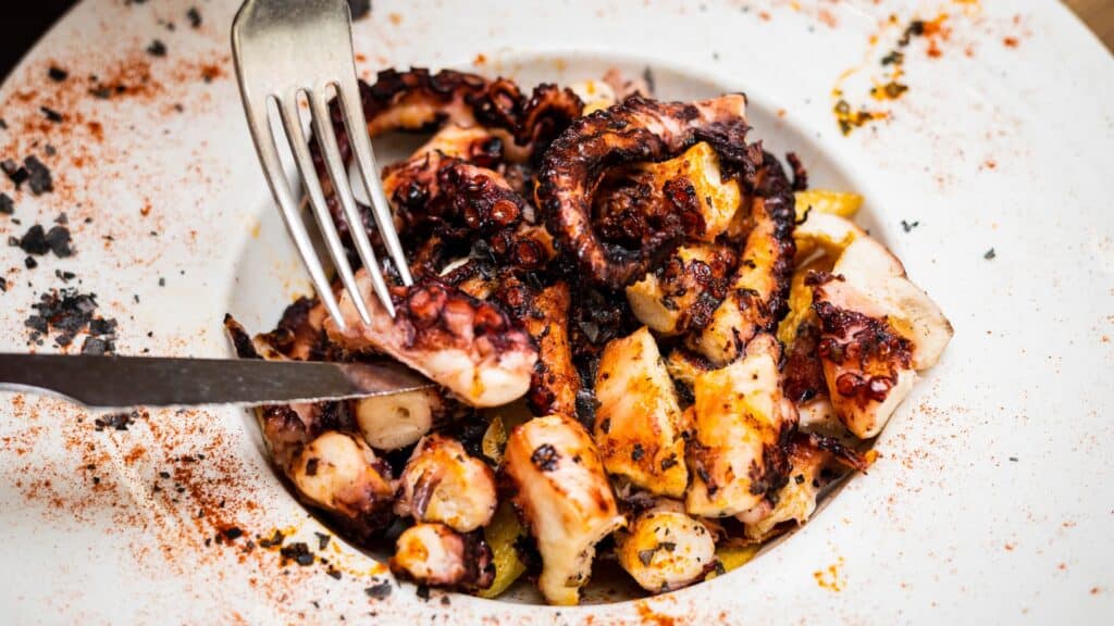 Plato de pulpo a la gallega Pulpo a la gallega con patatas y pimentón, presentado en un plato blanco.